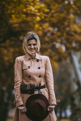 Fototapeta na wymiar Attractive blonde woman in autumn park in beige coat