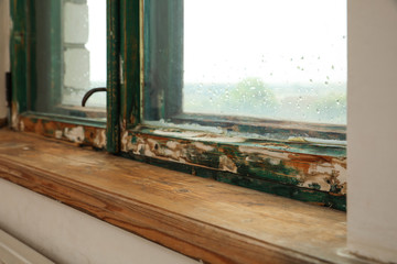 Old window with wooden sill in room, closeup