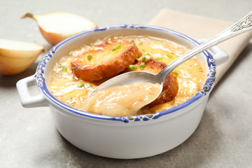 Tasty homemade french onion soup served on grey table, closeup