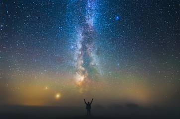 Naklejka na ściany i meble Landscape with Milky way galaxy and man standing against the stars, freedom concept