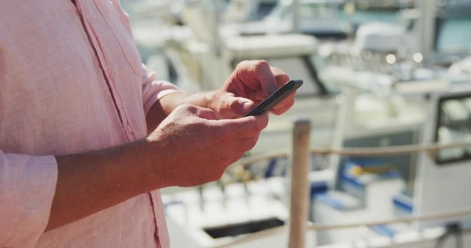 Side view mid section of a Caucasian man using his phone harbor side