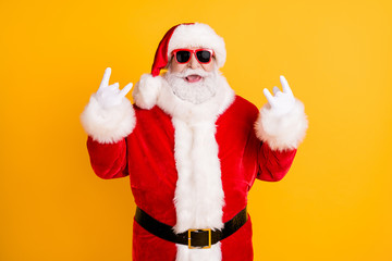 Portrait of his he nice funny comic cheerful cheery white-haired Santa St Nicholas showing double horn sign having fun isolated bright vivid shine vibrant yellow color background