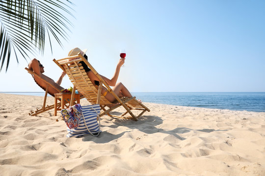 Couple with wine on sunny beach at resort