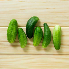 Small cucumbers on a light wooden background, top view