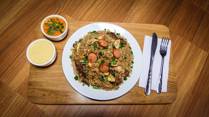 Peruvian food arroz chaufa, plate of fried rice with vegetables and different meats.