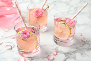 Refreshing drink with lemon and rose on white marble table