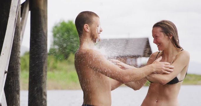 Caucasian couple having a good time on a trip to the mountains, standing by a lake, taking a shower