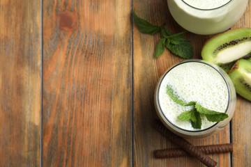 Tasty milk shake with kiwi on wooden table, flat lay. Space for text