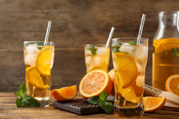 Delicious refreshing drink with orange slices on wooden table