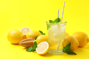 Natural freshly made lemonade with squeezer on yellow background. Summer refreshing drink