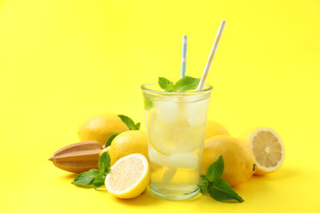 Natural freshly made lemonade with squeezer on yellow background. Summer refreshing drink