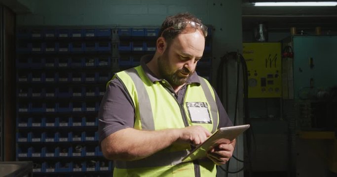 Caucasian male factory worker at a factory wearing a high vis vest working
