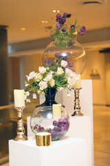 purple and white tulips in a round vase and a black vase.