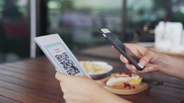 Women's hands are using  the phone to scan the qr code to select food menu. Scan to get discounts or pay for food. The concept of using a phone to transfer money or paying money online without cash.