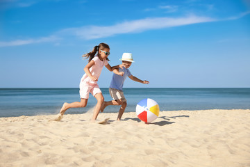 Cute little children playing with inflatable ball on sandy beach