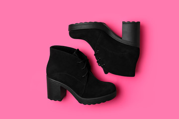 Stylish black female boots on pink background, flat lay