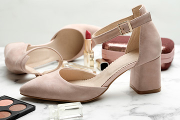 Naklejka premium Stylish shoes and cosmetics on white marble table, closeup