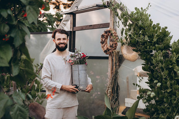young man, a farmer who is fond of growing wildflowers stands with freshly cut flowers near the...