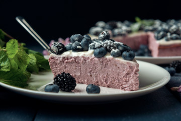 Piece of cottage cheese casserole decorated with blackberry and blueberry on white dessert plate. Close-up.