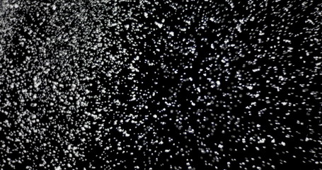 Cloud of shiny snowflakes floating in the air. The shot was taken while the snowflakes were on an isolated black background.