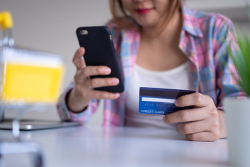 Close up female hands holding credit card and smartphone. Woman paying online,using banking service, entering information, Pay bills ,shopping concept.