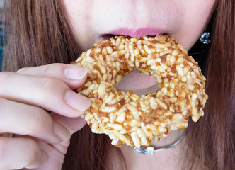 Woman is biting Donut made from rice cracker, sugar cane