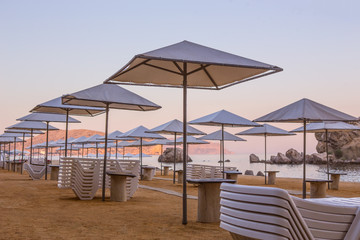 beach with parasols and plastic sun loungers.