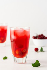 Fototapeta na wymiar Summer delicious refreshing cherry compote with pulp and with ice in glasses on a white background