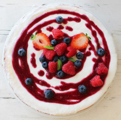Top view of whole cheesecake with berries and coulis on top