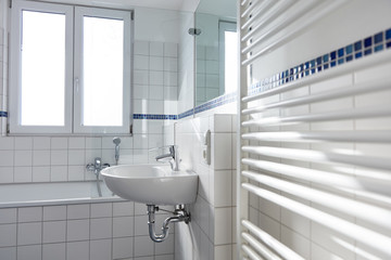 Waschbecken in hellem Bad mit Heizkörper und Fenster