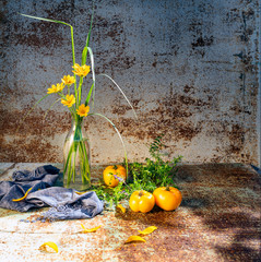 Summer yellow simple flowers in a glass vase against the background of shabby wall.