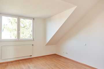 Leerer Raum in Dachgeschosswohnung mit Fenster und Heizung