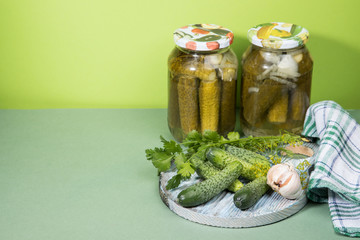 Two cans of pickles and gherkins. Pickled pickles on a round wooden chopping Board with herbs. A place for copy space. Horizontal orientation