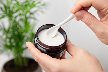 Female hand applying pure shea butter. Anti-aging treatment. Skin and hair care product, natural cosmetics.