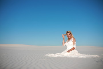 Fototapeta na wymiar Beautiful bride in the desert on white clean sands 