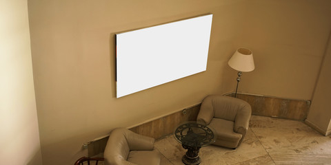 empty white picture hanging on concrete wall in hotel hall interior