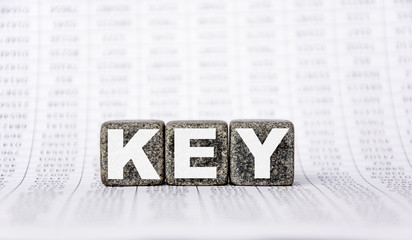 three stone cubes on the background of white financial statements, tables with the word key. Strong business concept