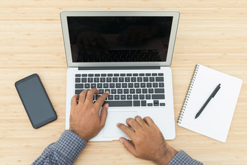 Top view of businessman typing keyboard using laptop of working project on the wooden table desk.