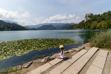 A small girl is sitting on the bank of lake bled in slovenia