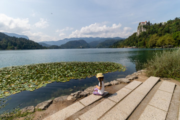 Fototapeta premium A small girl is sitting on the bank of lake bled in slovenia