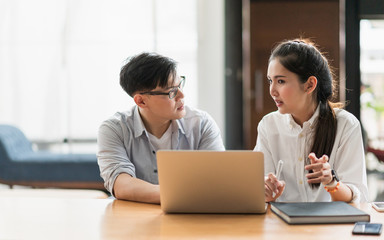 Asian business people man and woman conference talking and working with laptop together. Young couple work at home.
