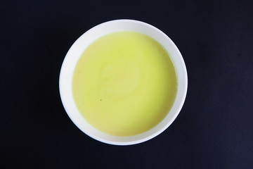 white plate with cream soup of zucchini, potatoes, cream, onions on a black background top view . cooking at home