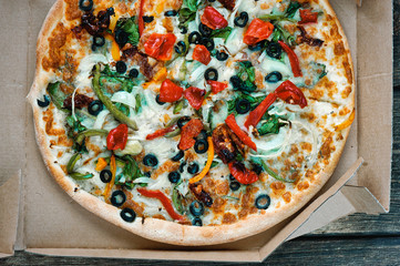 Delicious fresh pizza served on wooden table background. Summer dinner or lunch. Freshly baked Italian vegetarian pizza with vegetables. Top view.