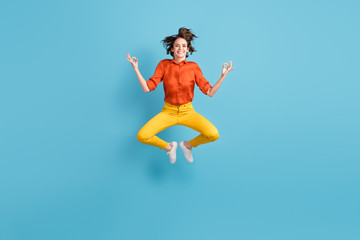 Fototapeta na wymiar Full length photo of attractive funny lady jump high up positive energy emotions practice yoga om position in flight wear orange shirt yellow trousers sneakers isolated blue color background