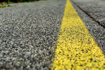 Structure of granular asphalt. Close up of an Asphalt texture with a yellow line road marking. Abstract road background.