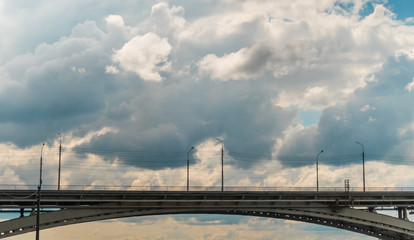 Empty bridge against sky - side view. Sun beams shining through dramatic white clouds. Urban, infrastructure development, transportation concept