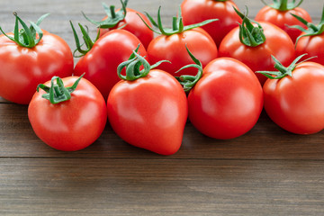 Fresh tomatoes lie on a wooden background.