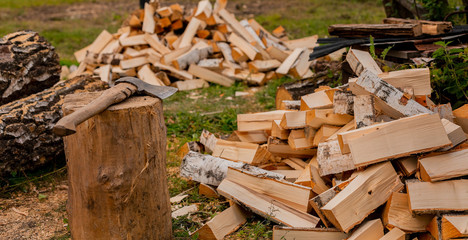 A pile of birch firewood on the green grass. Split logs. Sawdust. Selective focus.