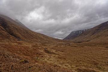 Fototapeta na wymiar Looking down the Glacial Valley of Glen Etive, with low cloud covering the Mountain Tops with the last remnants of snow clinging to the Slopes