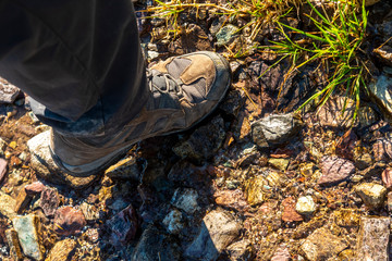 hiking boot on the ground over a small water stream